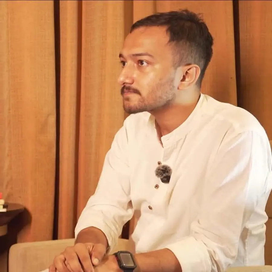 Souvik Ghosh seated, in a white kurta, listening.