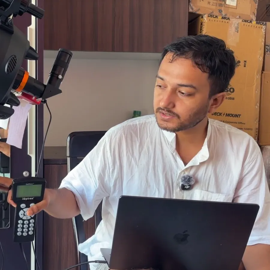 Souvik Ghosh at a laptop, holding the hand controller of the Purākaash telescope.