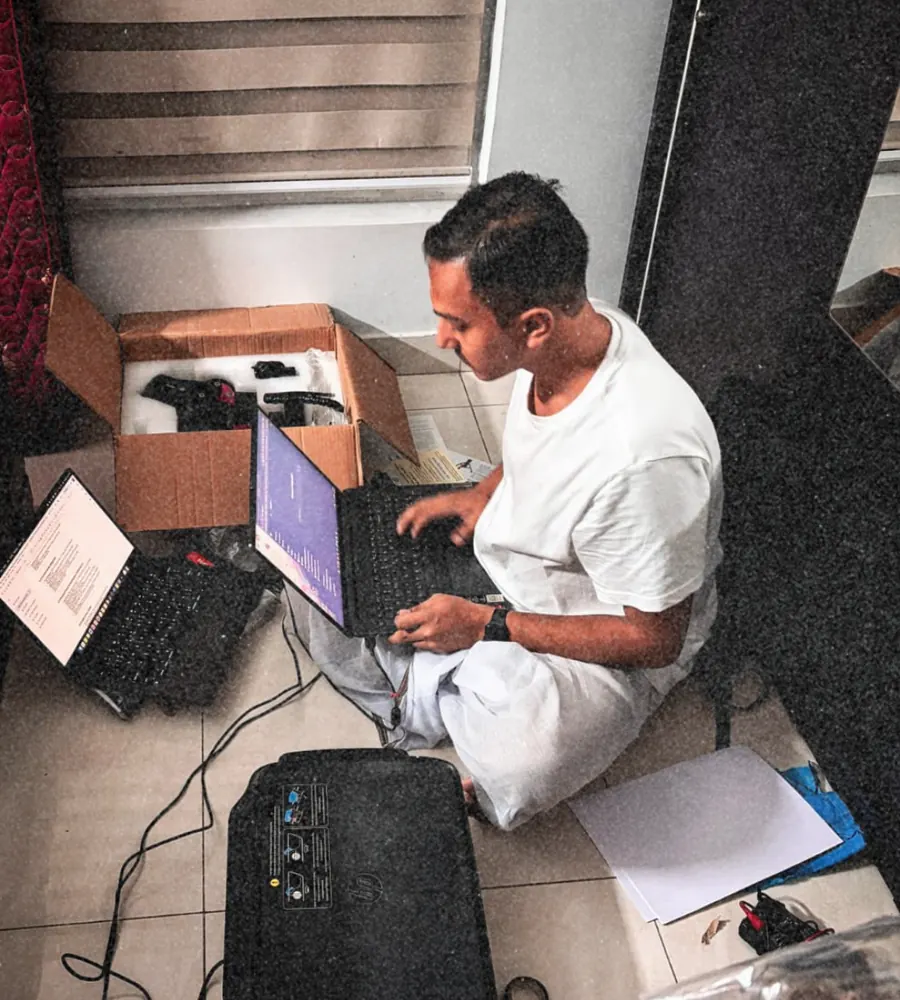 Souvik Ghosh sitting on the floor with two laptops and the mount’s case, working on the control software.